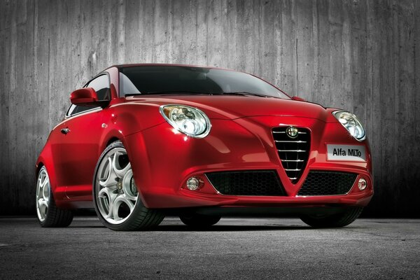 Қара фонда алдыңғы жағында қызыл alfa romeo көлігі