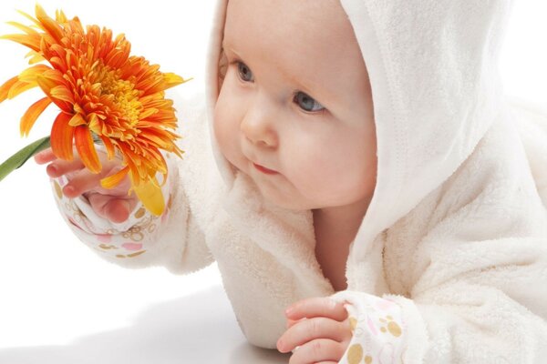 Cute baby looks at a bright flower