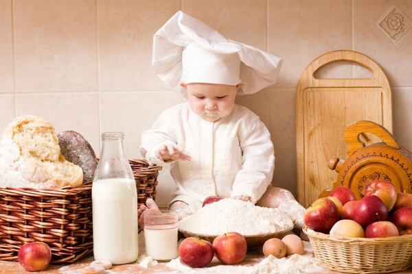 Bébé cuisinier sur la table et le visage dans la farine