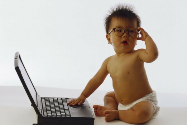 Photo of a baby in glasses with a laptop