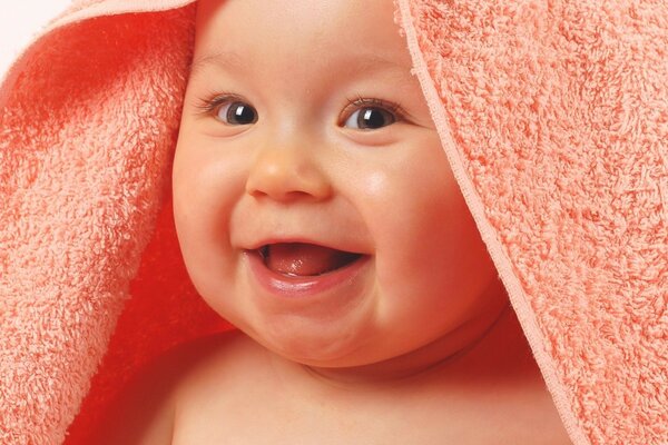 A child wrapped in a towel smiles