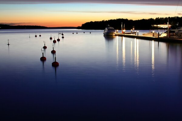 Der Sonnenuntergang erhellt die Oberfläche des Sees, die Küste spiegelt sich im dunklen Wasser wider