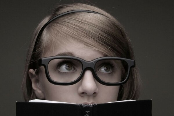Photo of a girl with glasses holding a book in her hands