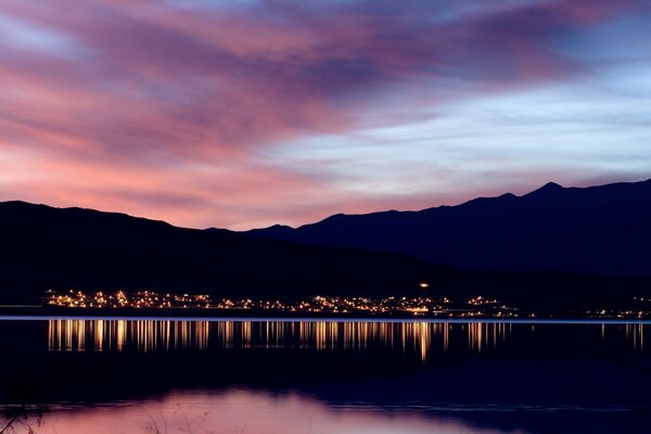 The coast in lights at sunset is reflected in the coastal waters