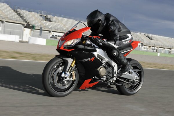 Мужчина едет на мотоцикле aprilia rsv4 по гоночной трассе