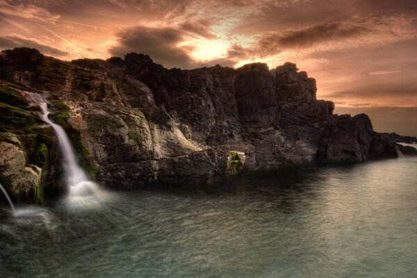 Steep seashore with waterfall