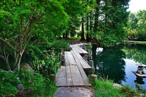 A bridge in a green garden and a lake