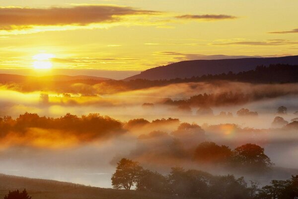 Amanhecer de fogo acima das nuvens com neblina travada