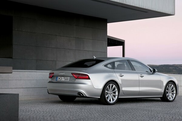 Audi am grauen Gebäude bei Sonnenuntergang