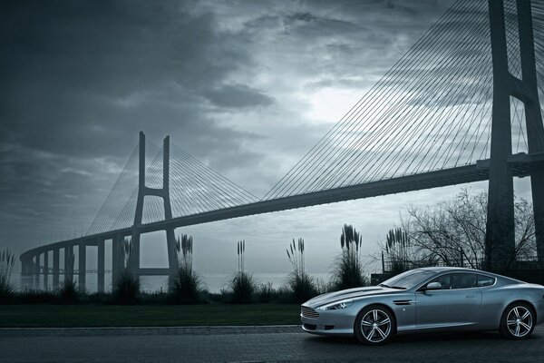 A gray car, a bridge against a gray sky