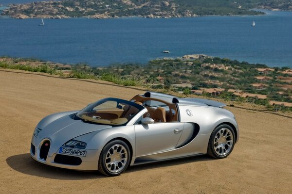 Grey bugatti sports car on the beach by the water