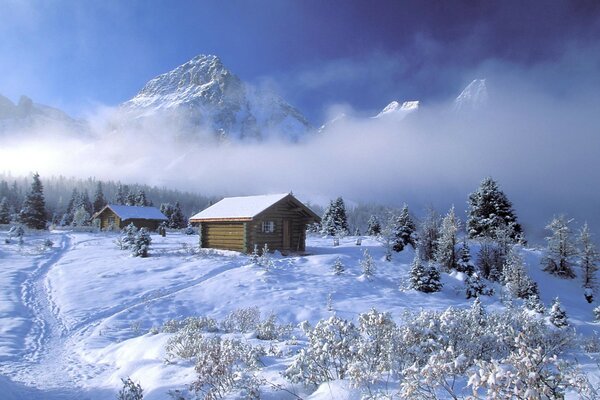 Capanna nella neve sullo sfondo delle montagne