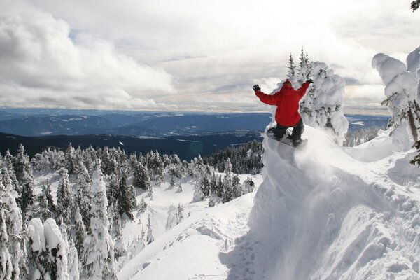 A guy on a snowboard descends from the mountainside