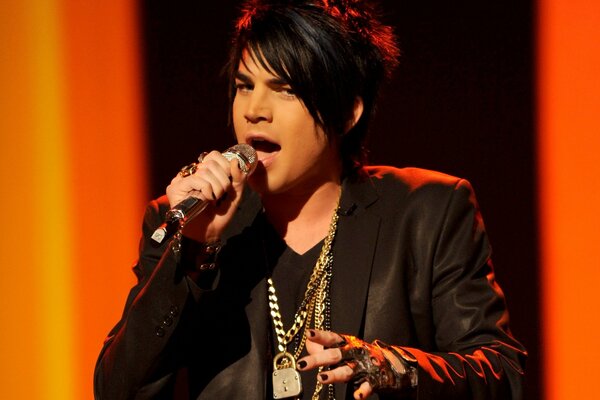 A dark-haired musician in a rock image with a microphone