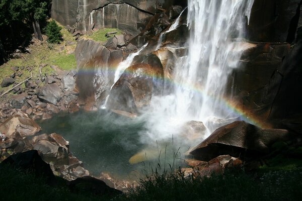 Waterfall on the background of mountains , rainbows and green trees