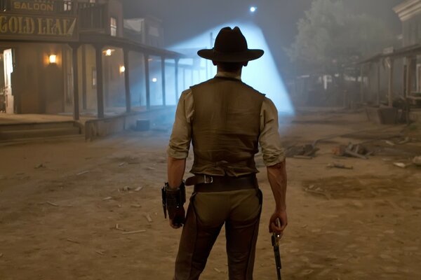 A cowboy man with a revolver stands with his back in the middle of the street