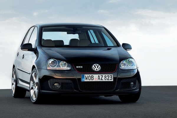 A black Volkswagen car stands on the asphalt against the sky