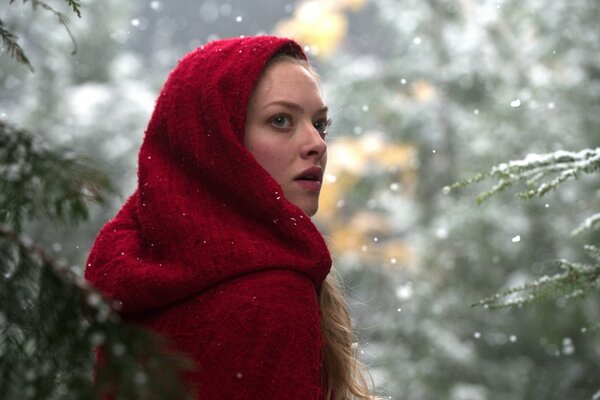 Chica en un cálido abrigo rojo en invierno en el bosque