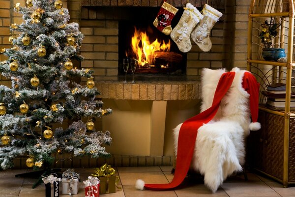 A fireplace a Christmas tree and an armchair with a blanket