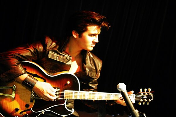 A musician in a leather jacket with a guitar