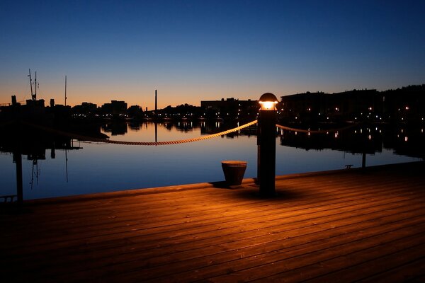 Einsame Laterne am Wasser nach Sonnenuntergang Silhouette eines Baumes auf einem lila Kreuz Hintergrund