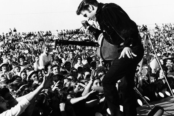 Black and white photo. Elvis on stage in front of a crowd