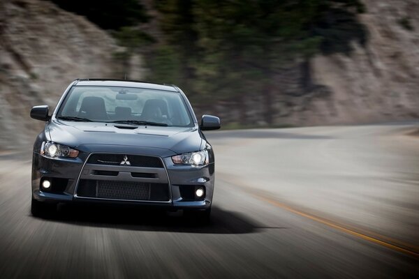 A mitsubishi car racing along an asphalt highway