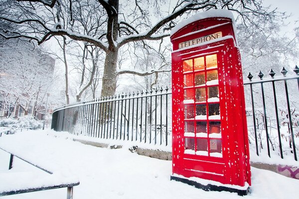 Cabina telefonica luminosa in mezzo a una strada innevata