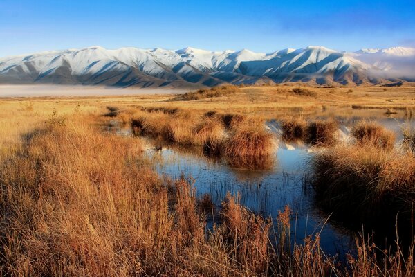 Karlı dağların arka planında gölün fotoğrafı