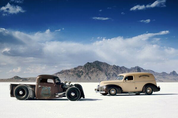 Dos coches retro de pie en el desierto en medio de las montañas