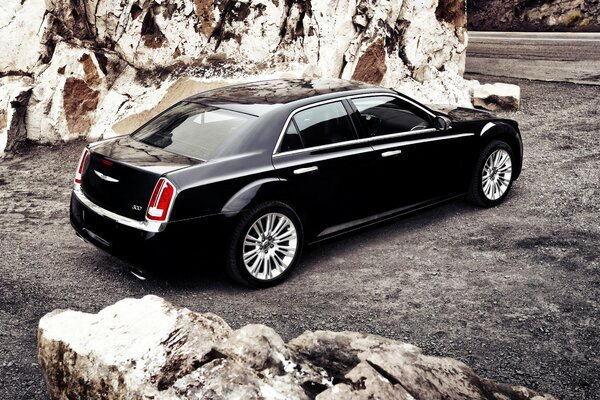 Black car on the road near the rocky wall