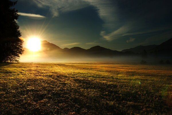 Sonnenaufgang auf dem Hintergrund von Bergen und Feldern