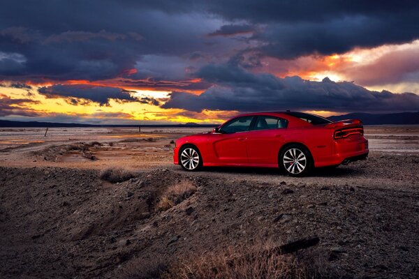 A red car rides into the sunset