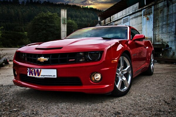 Chevrolet rouge se dresse sur un chemin de terre sur fond de montagnes