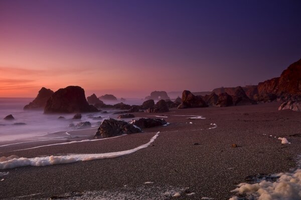 الشاطئ البري عند غروب الشمس مع رغوة البحر