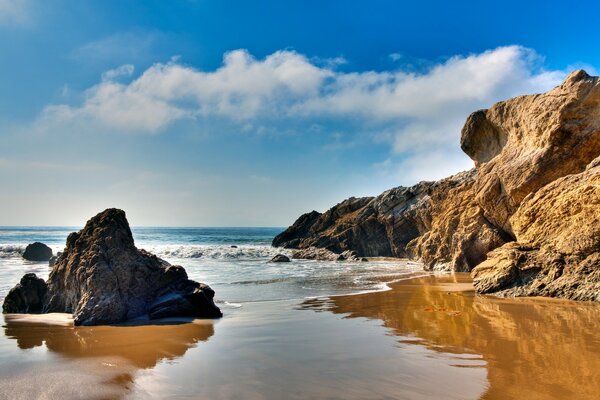 Sandy beach by the ocean with boulders