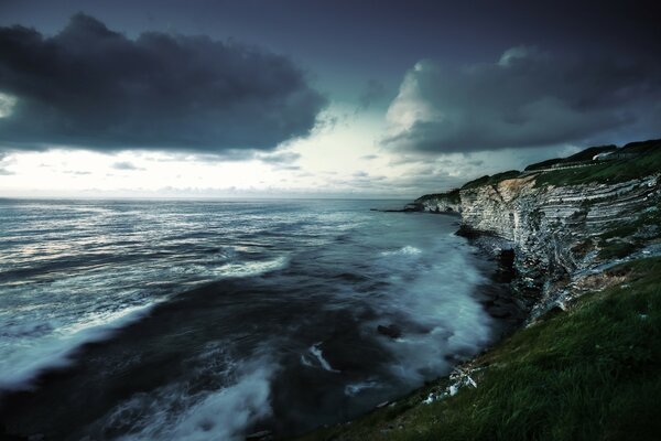 Black waves crashing against the rocky shore