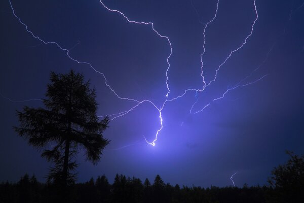 A storm paints a landscape with lightning in the night sky