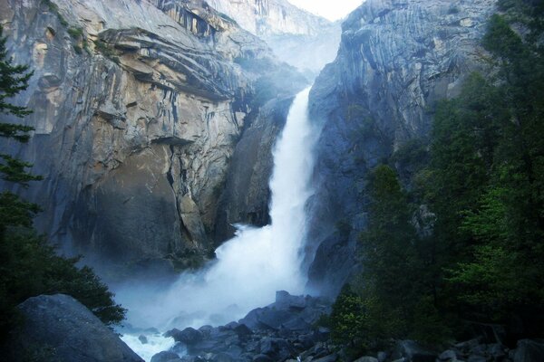 Una poderosa cascada que cae de las montañas rocosas