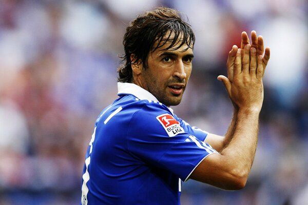 A football player in a blue uniform applauds