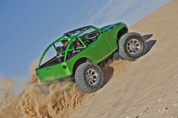 A green jeep on a sandy area climbs into the ascent