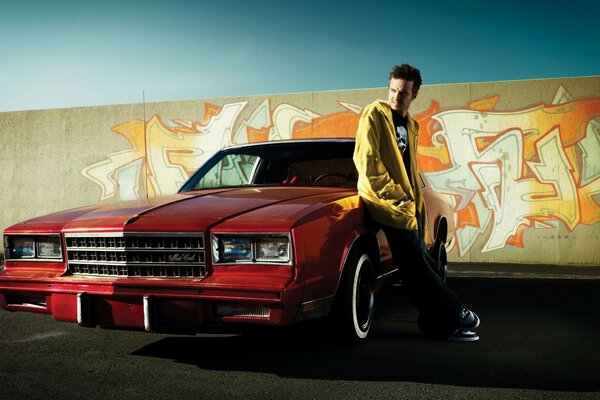 A young guy next to a red car