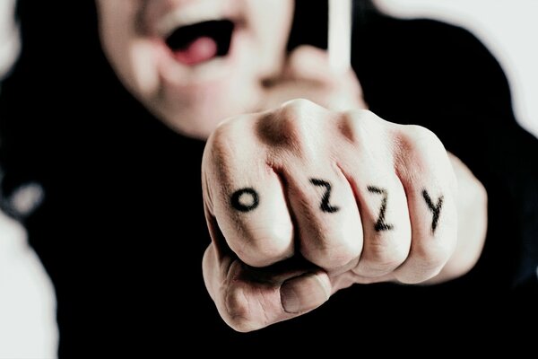 Ozzy Osbourne shows a fist with an inscription to the camera