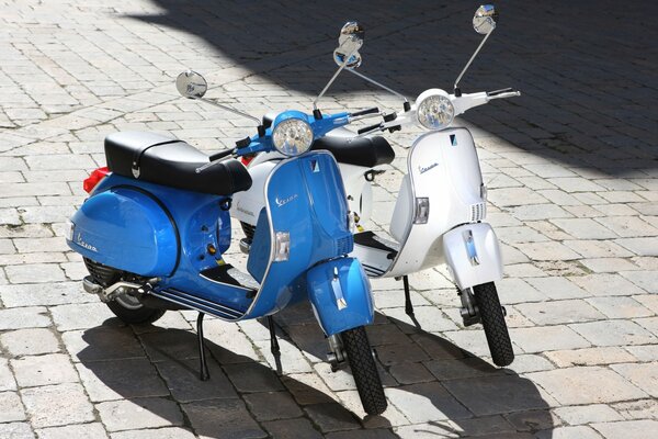 Two mopeds are standing on the street