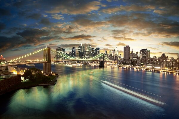 Vista nocturna del puente iluminado sobre el río con nubes en el cielo