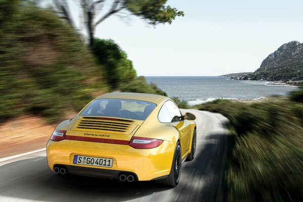 Porsche amarelo viaja ao longo do mar