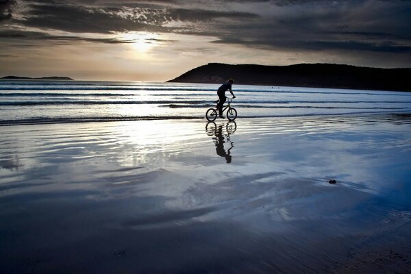 A cyclist riding along the coast at sunset