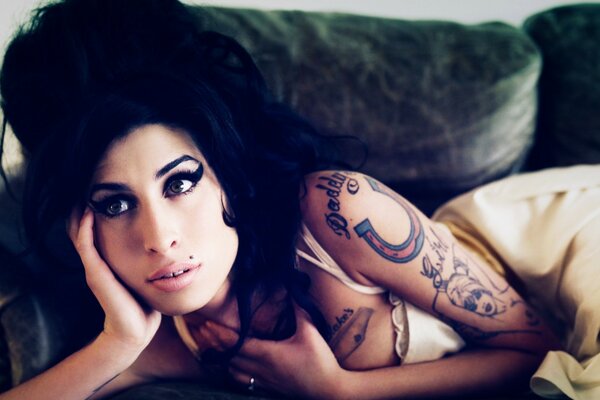 Beautiful singer with a tattoo on the bed