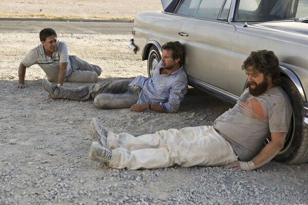 三名男子躺在车后