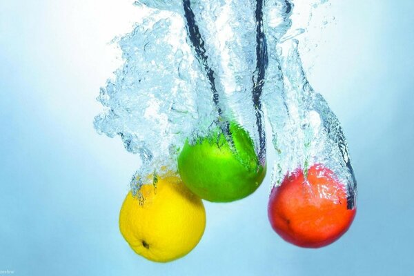 Tre mele di colore diverso cadute in acqua